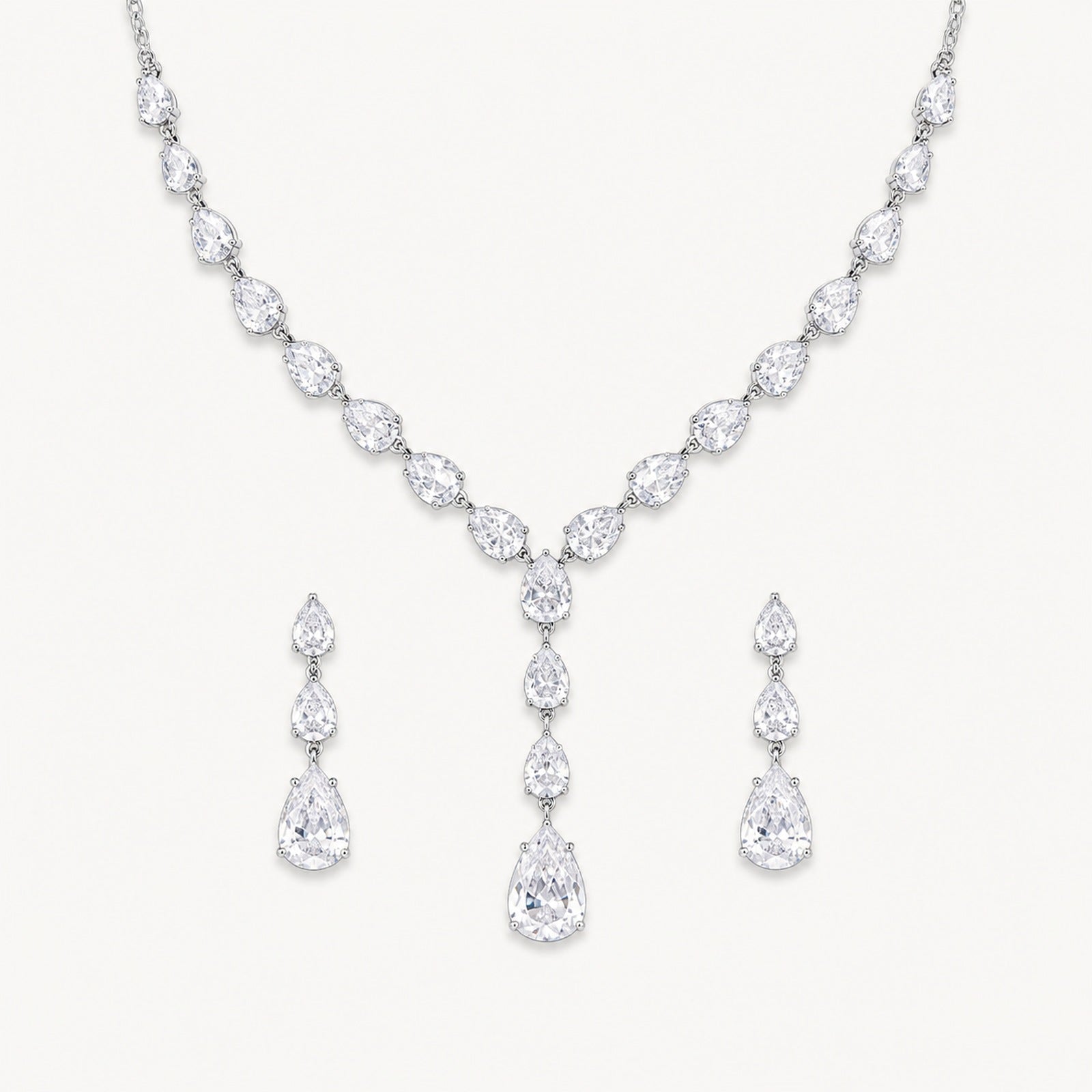 The Delphine Pear-Drop Necklace & Earrings Set on a warm white background
